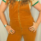 Person wearing a mustard yellow corduroy jumpsuit with a plain background