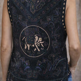 Black embroidered vest with intricate designs and a logo on the back, worn by a person.