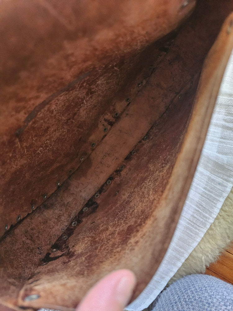 Brown leather glove with visible wear and tear, held by a hand.