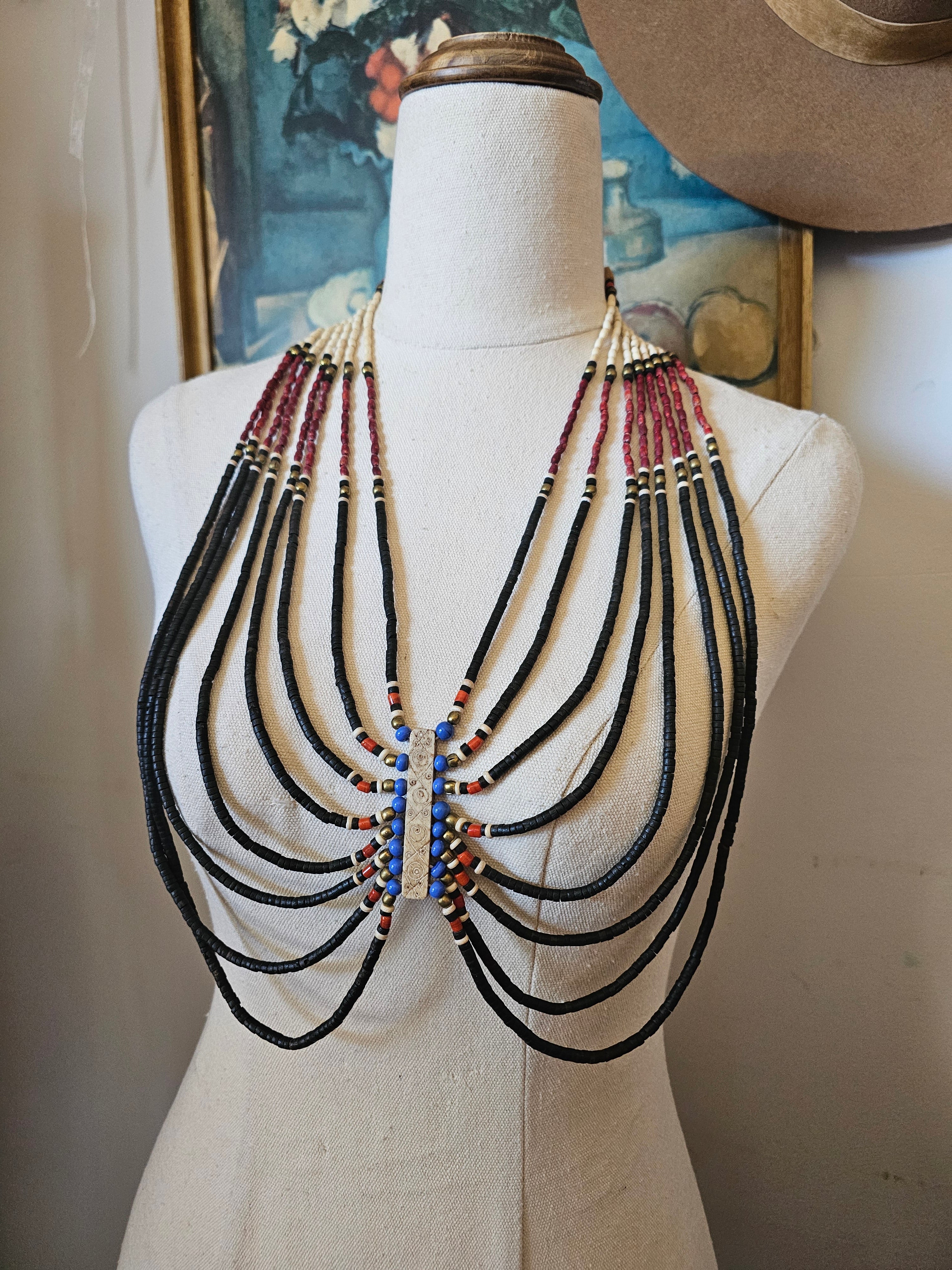 Set of necklaces displayed on a mannequin bust with a painting in the background