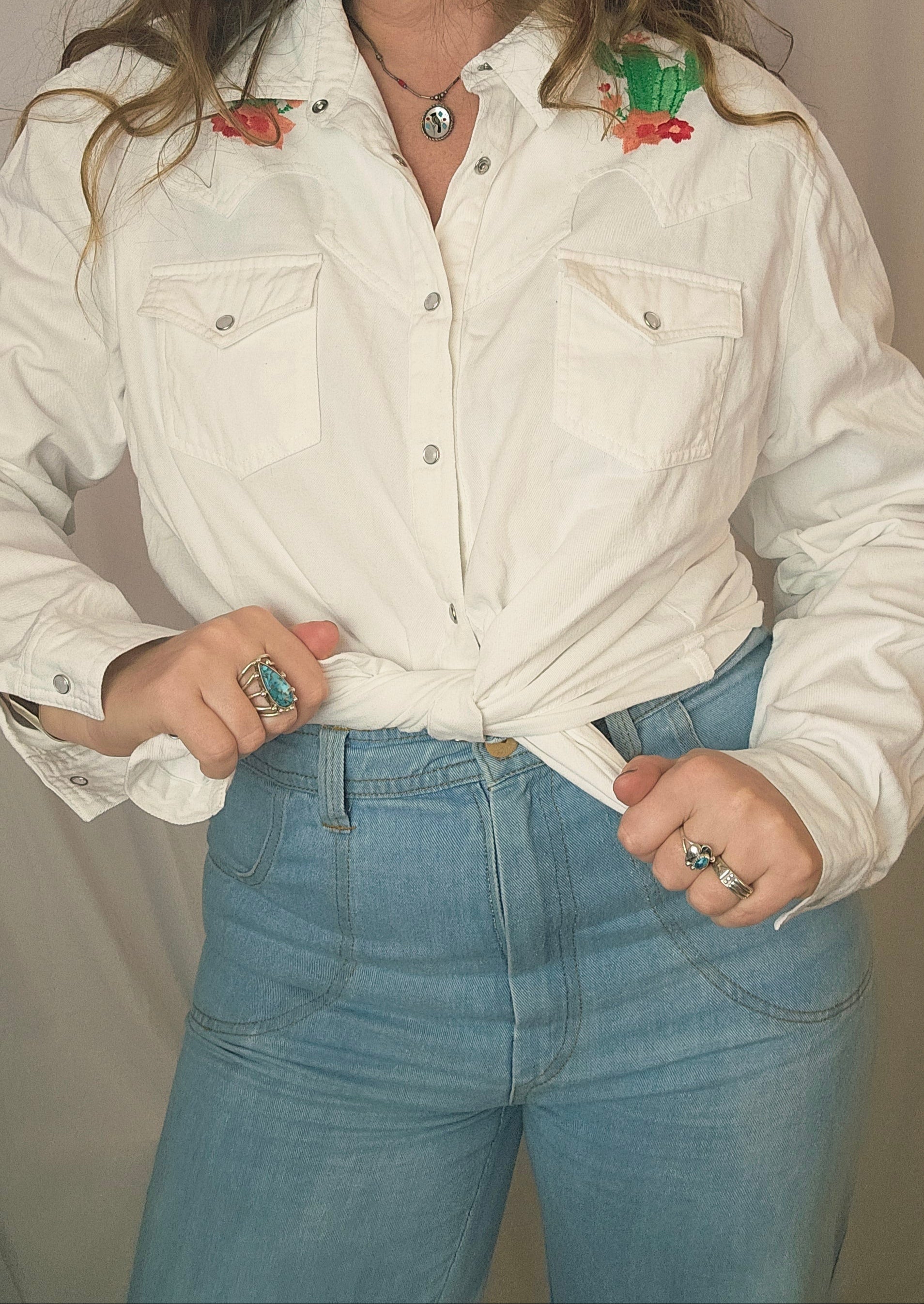 Person wearing a white jacket with decorative buttons on a plain background