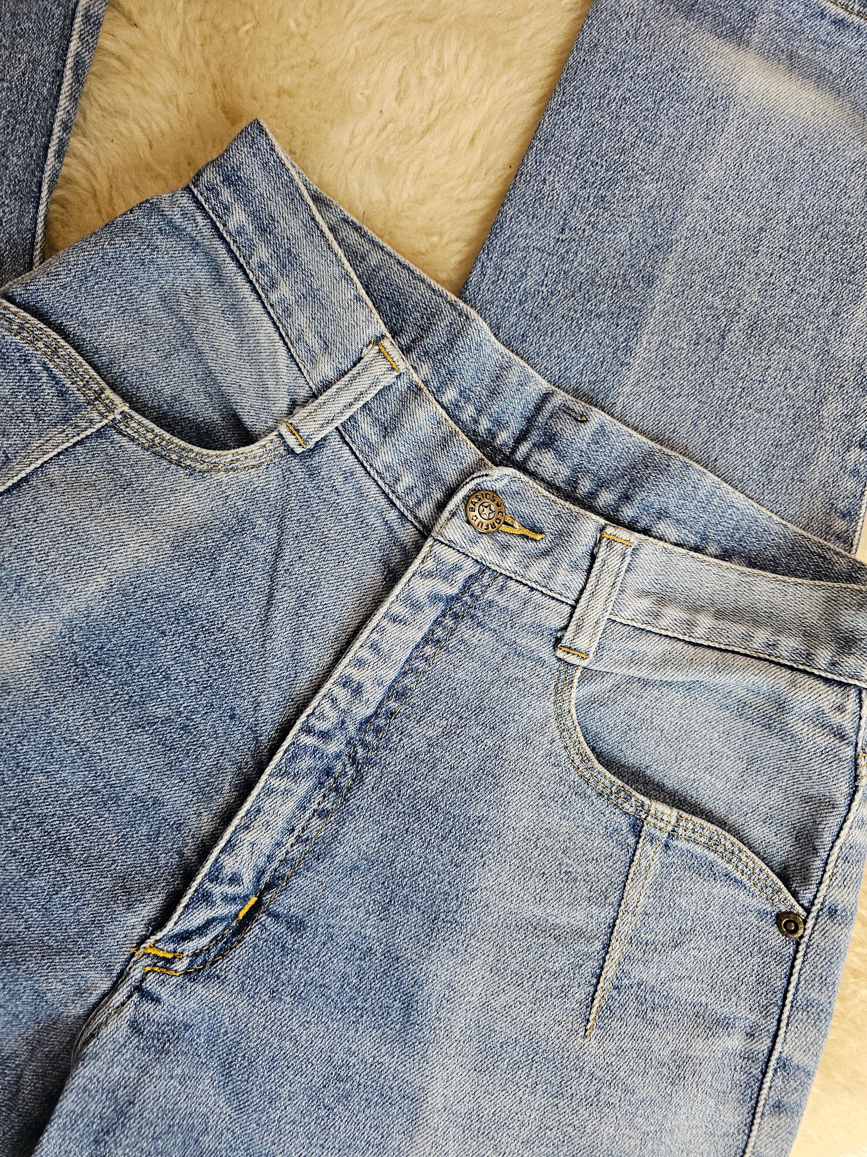 Close-up of blue denim jeans on a beige surface