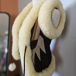 Pair of black shoes with white fuzzy bands on a blurred background