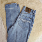 Folded blue jeans with a brand label on a beige surface