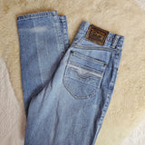 Folded blue jeans with a brand label on a beige surface