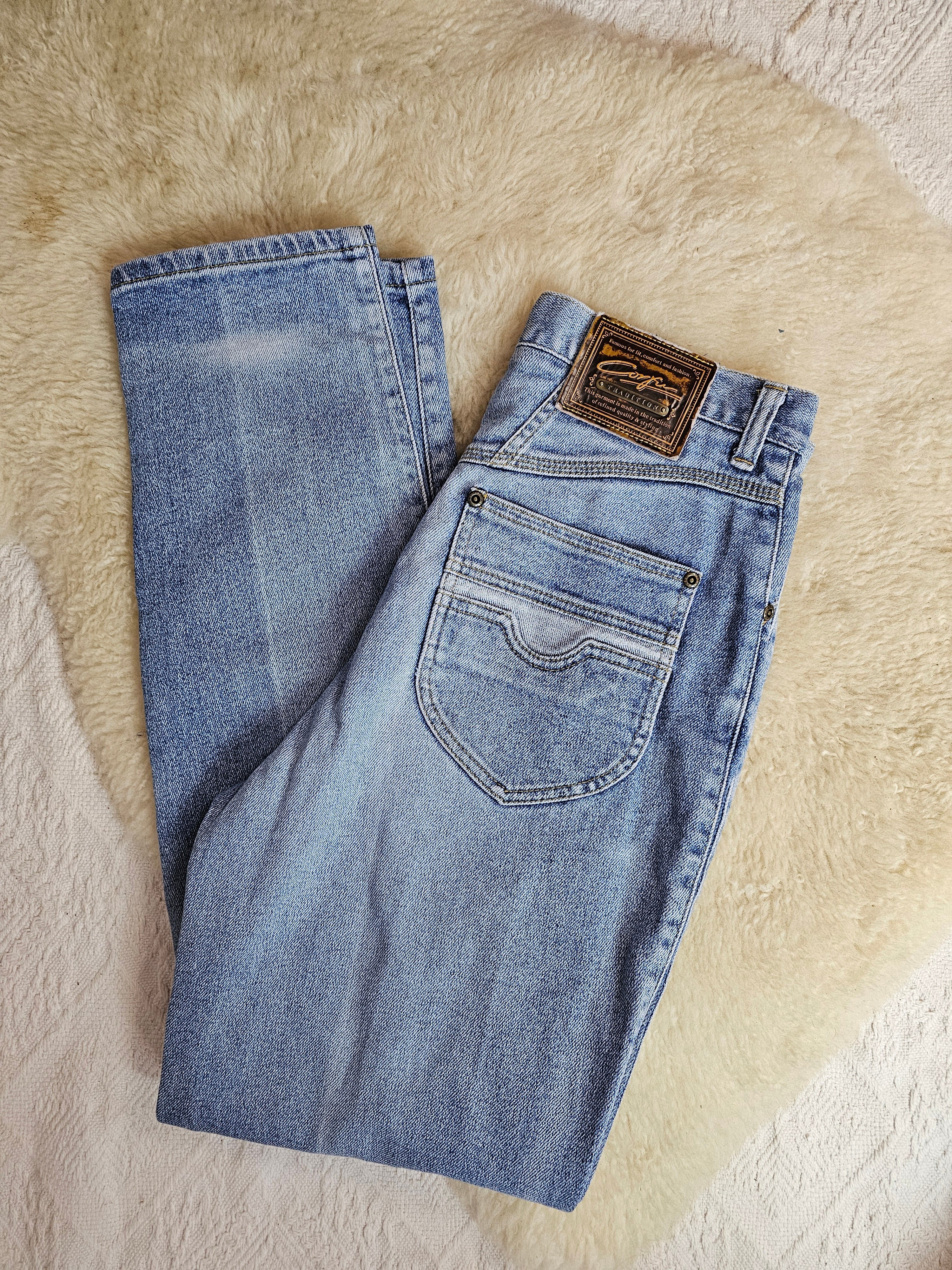 Folded blue jeans with a brand label on a beige surface