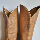 Pair of tan leather cowboy boots with intricate stitching on a white background