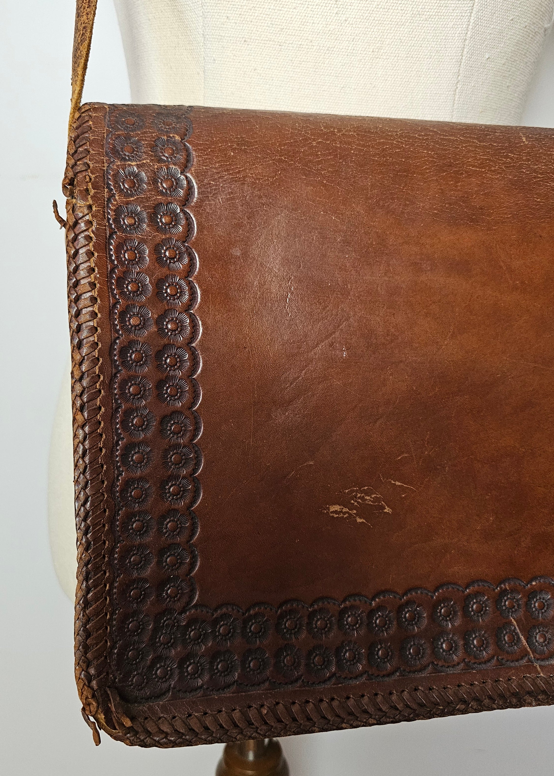 Brown leather handbag with decorative stitching on a white surface
