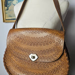 Close-up of a brown leather saddle pad on a horse with a blurred background