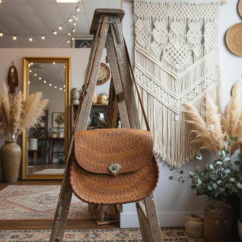 Close-up of a brown leather saddle pad on a horse with a blurred background