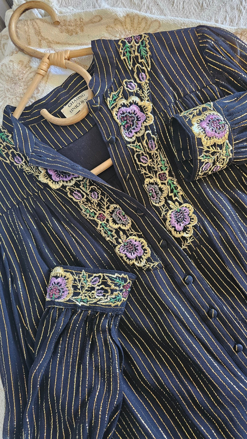 Close-up of a dark blue embroidered garment with floral patterns on a textured surface.
