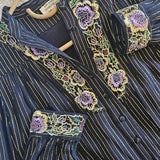 Close-up of a dark blue embroidered garment with floral patterns on a textured surface.