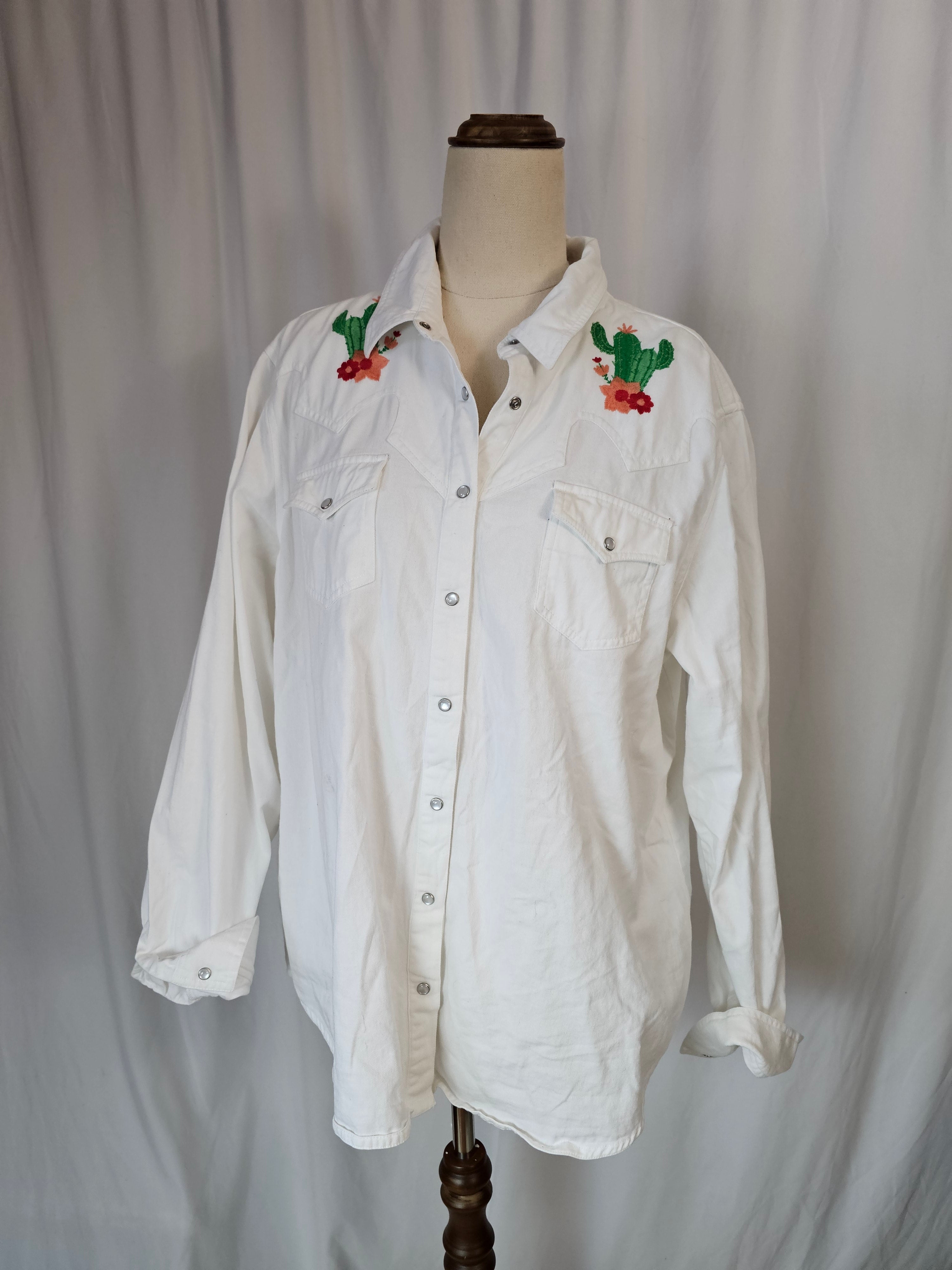 White shirt with embroidery on a mannequin against a plain background