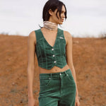 Woman wearing a green sleeveless top and pants in a desert-like setting