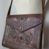 Brown leather handbag with floral embossing on a white surface