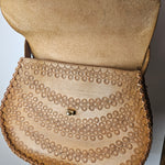Close-up of a beige handbag with a textured pattern on a blurred background