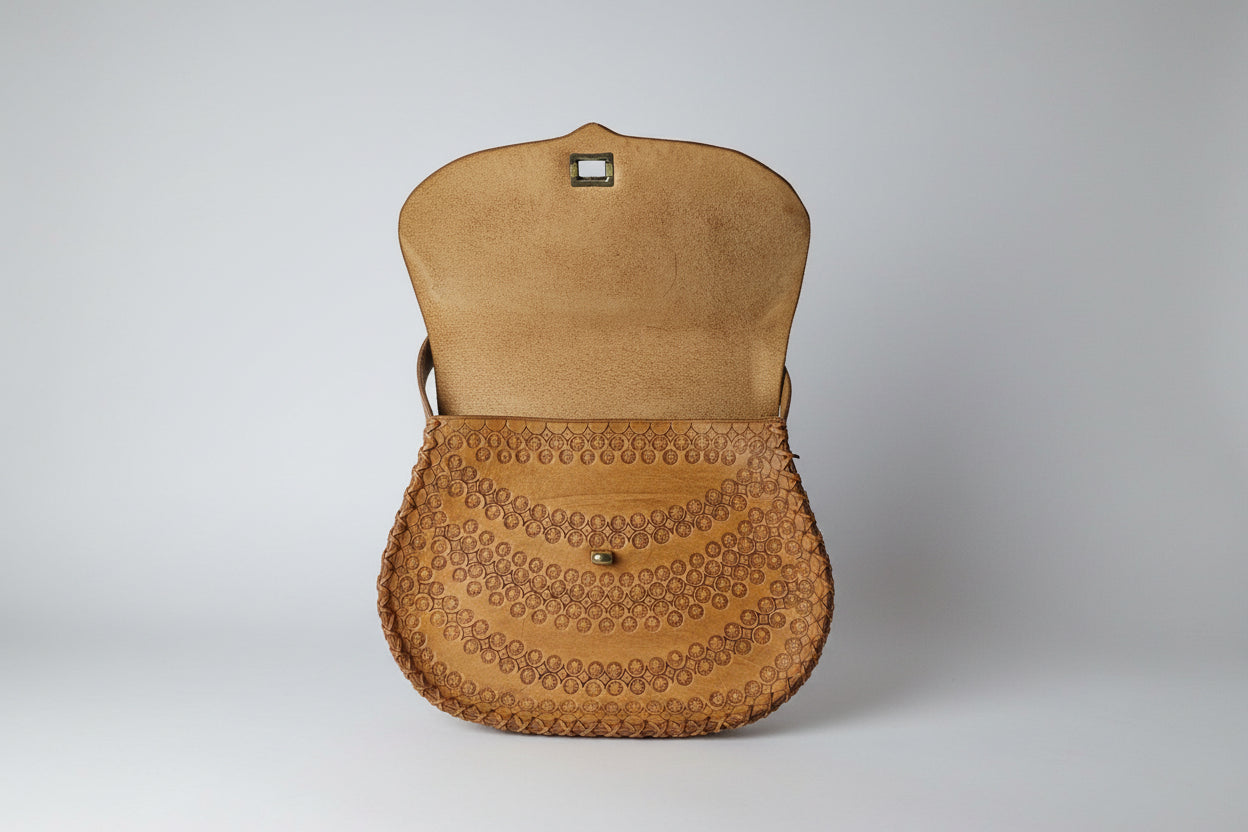 Close-up of a beige handbag with a textured pattern on a blurred background