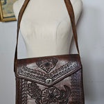 Brown leather handbag with intricate patterns on a white surface