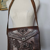 Brown leather handbag with intricate patterns on a white surface