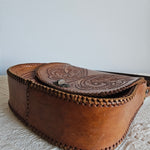 Brown leather pouch with intricate designs on a textured surface