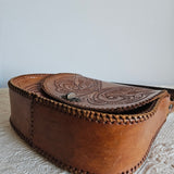 Brown leather pouch with intricate designs on a textured surface