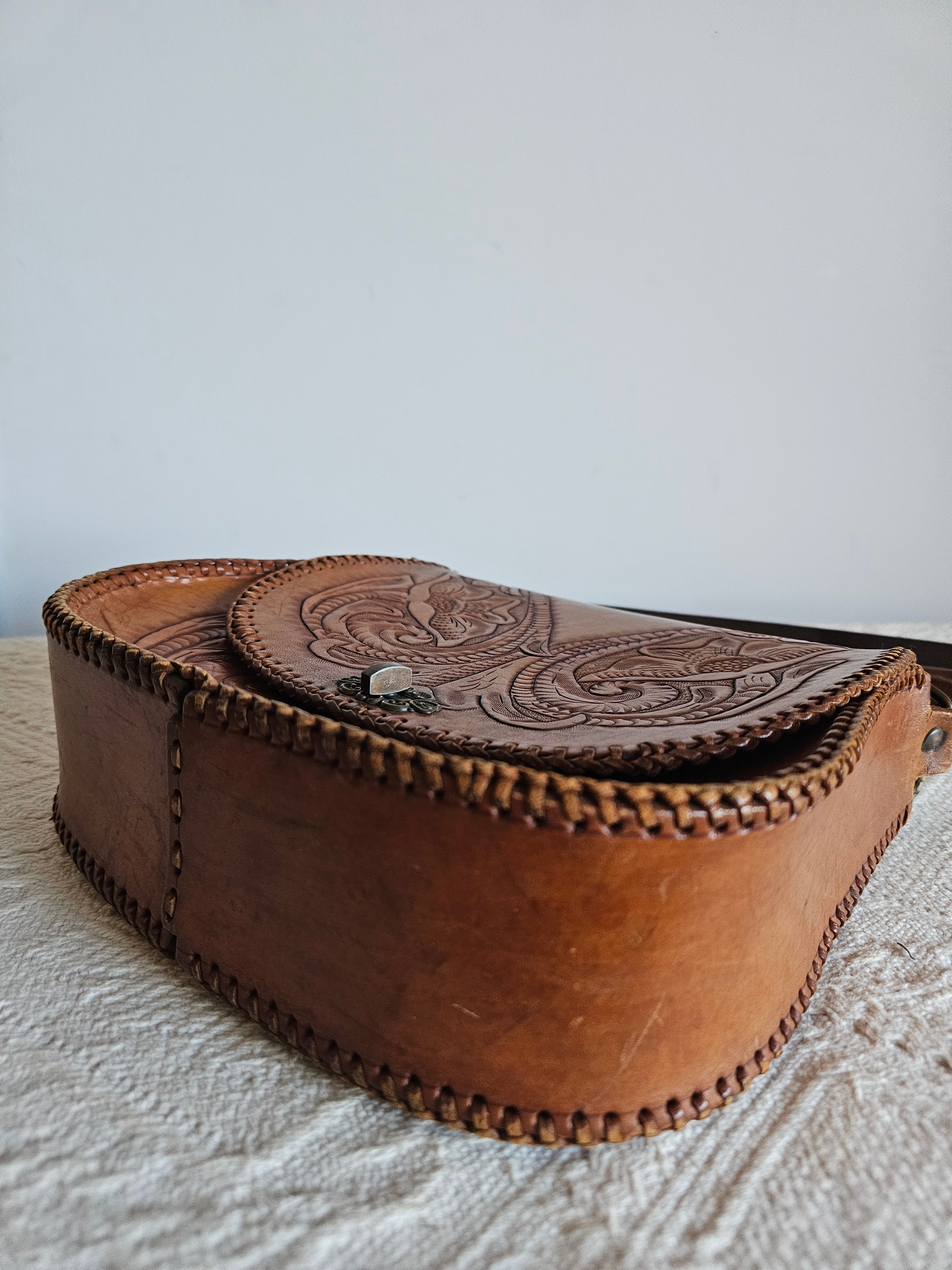 Brown leather pouch with intricate designs on a textured surface