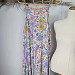 Floral-patterned belt on a mannequin against a white wall with decorative elements.