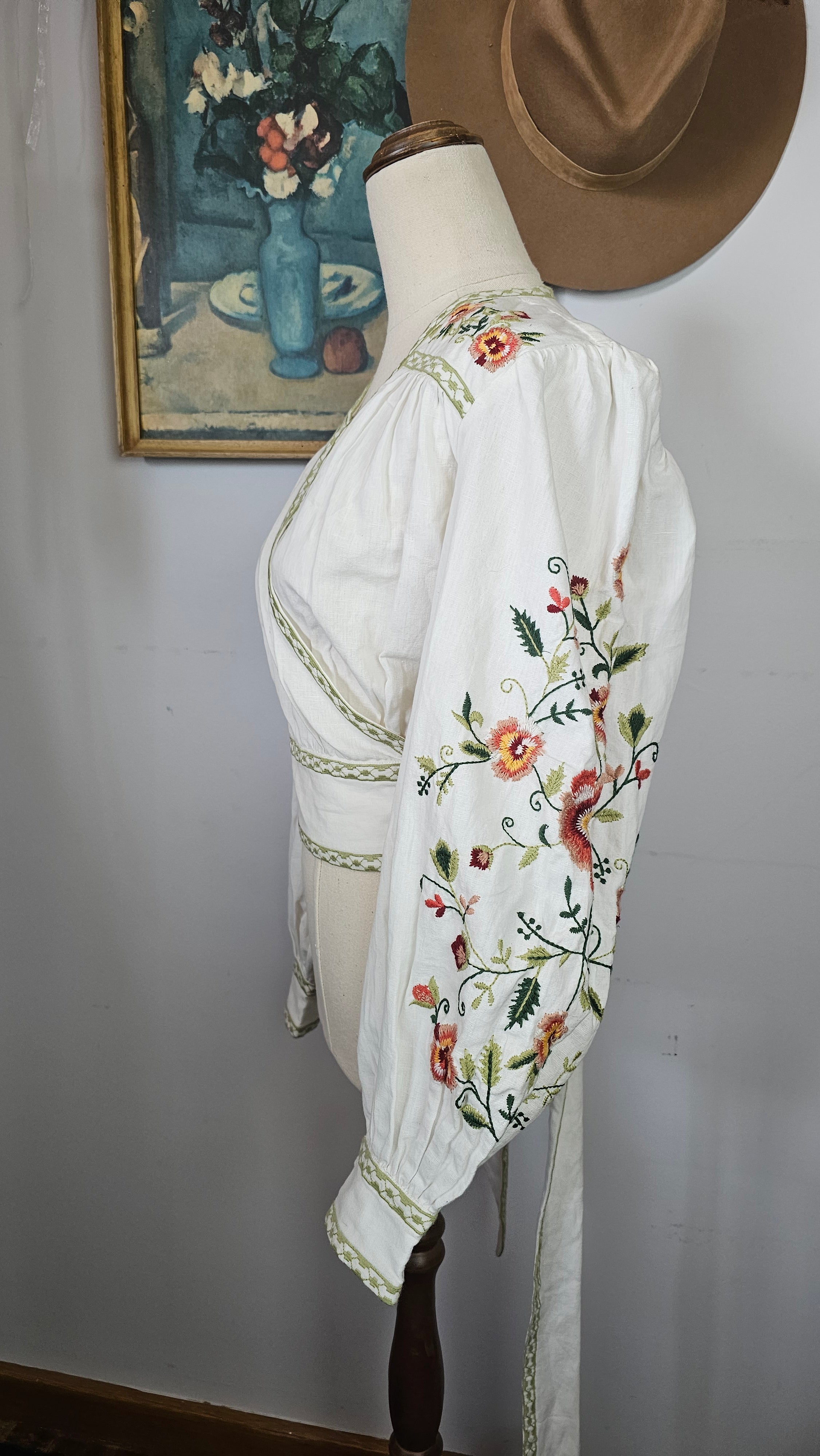 White embroidered blouse with floral patterns on a plain background