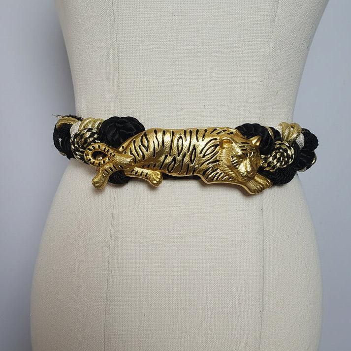Gold and black belt with tiger design on a mannequin against a white background