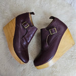 Pair of brown wedge shoes with wooden soles on a white fur surface