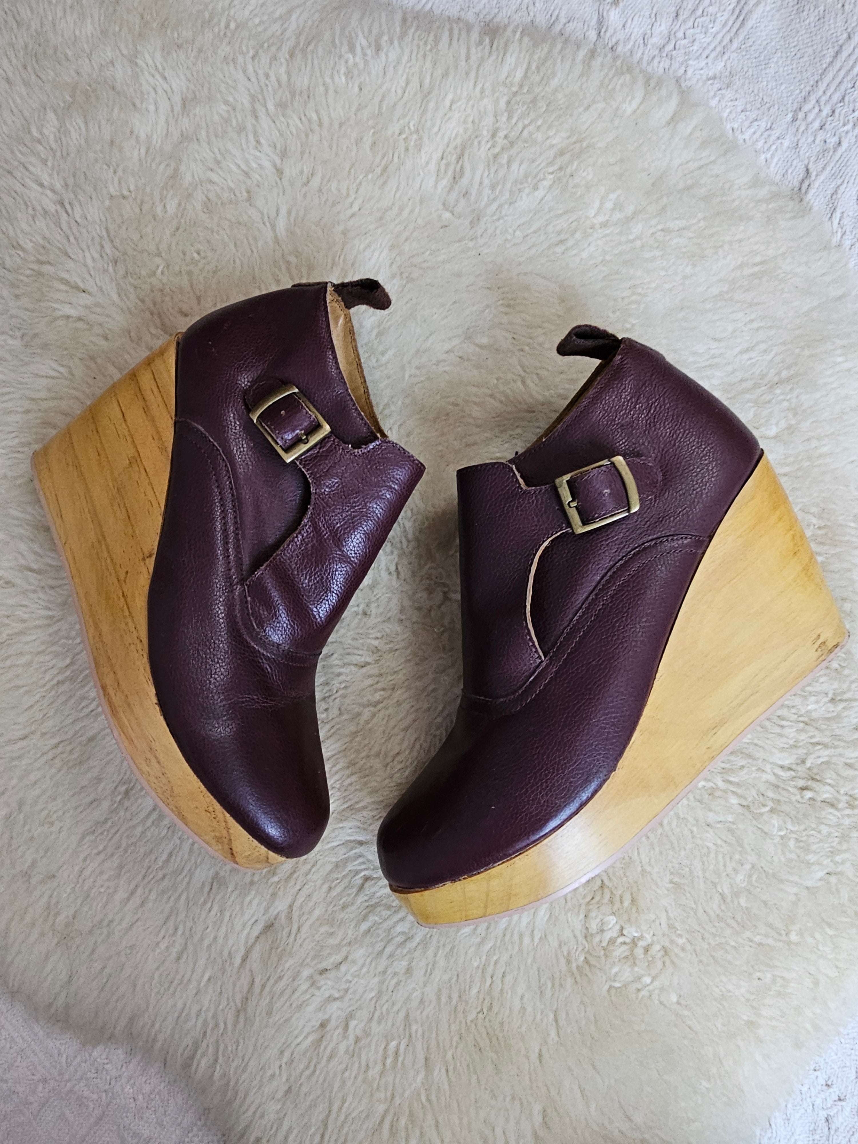 Pair of brown wedge shoes with wooden soles on a white fur surface