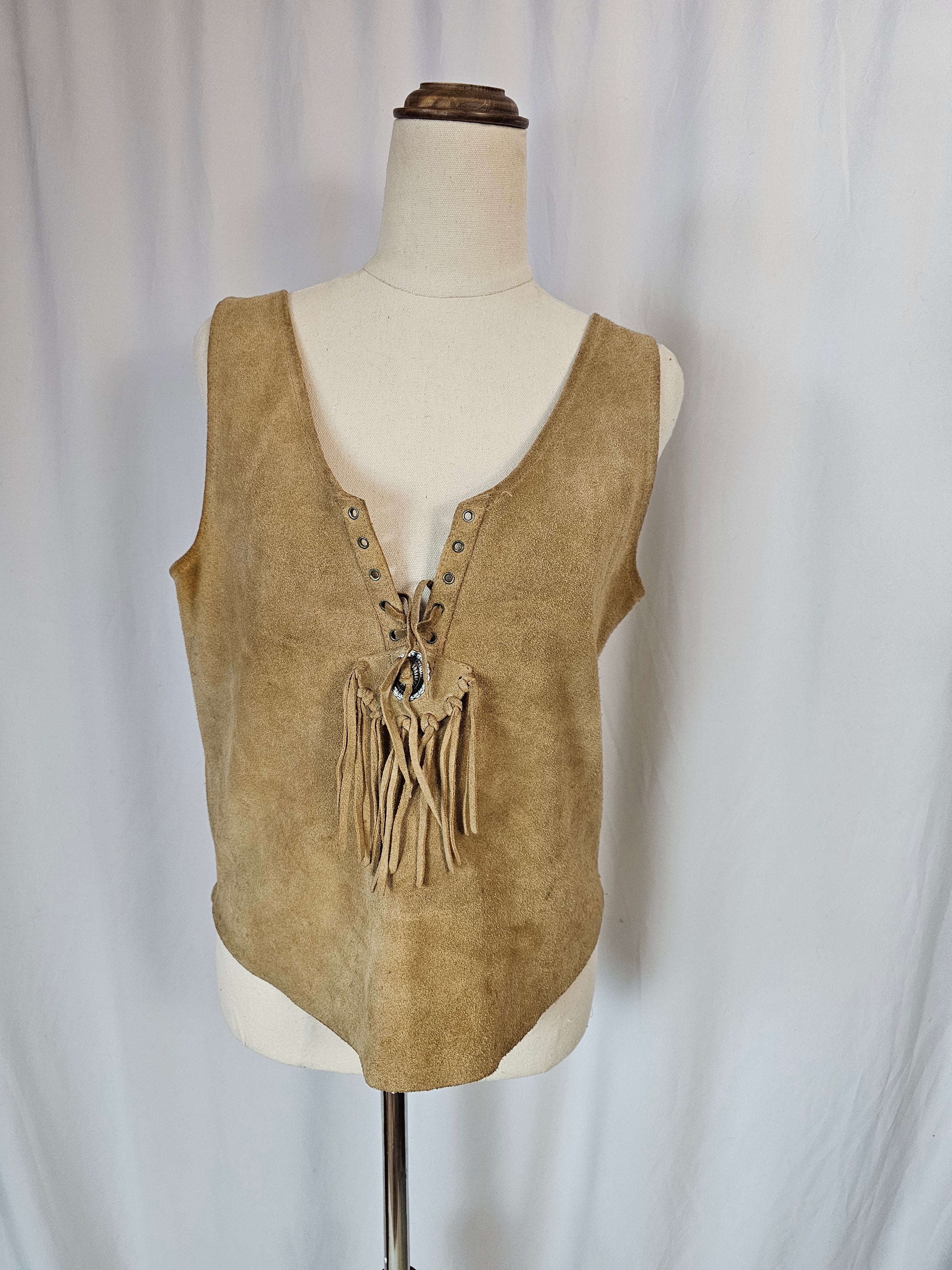 Tan leather saddle with fringes on a mannequin against a neutral background