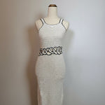 Mannequin wearing a white knitted dress with black patterns on a plain background