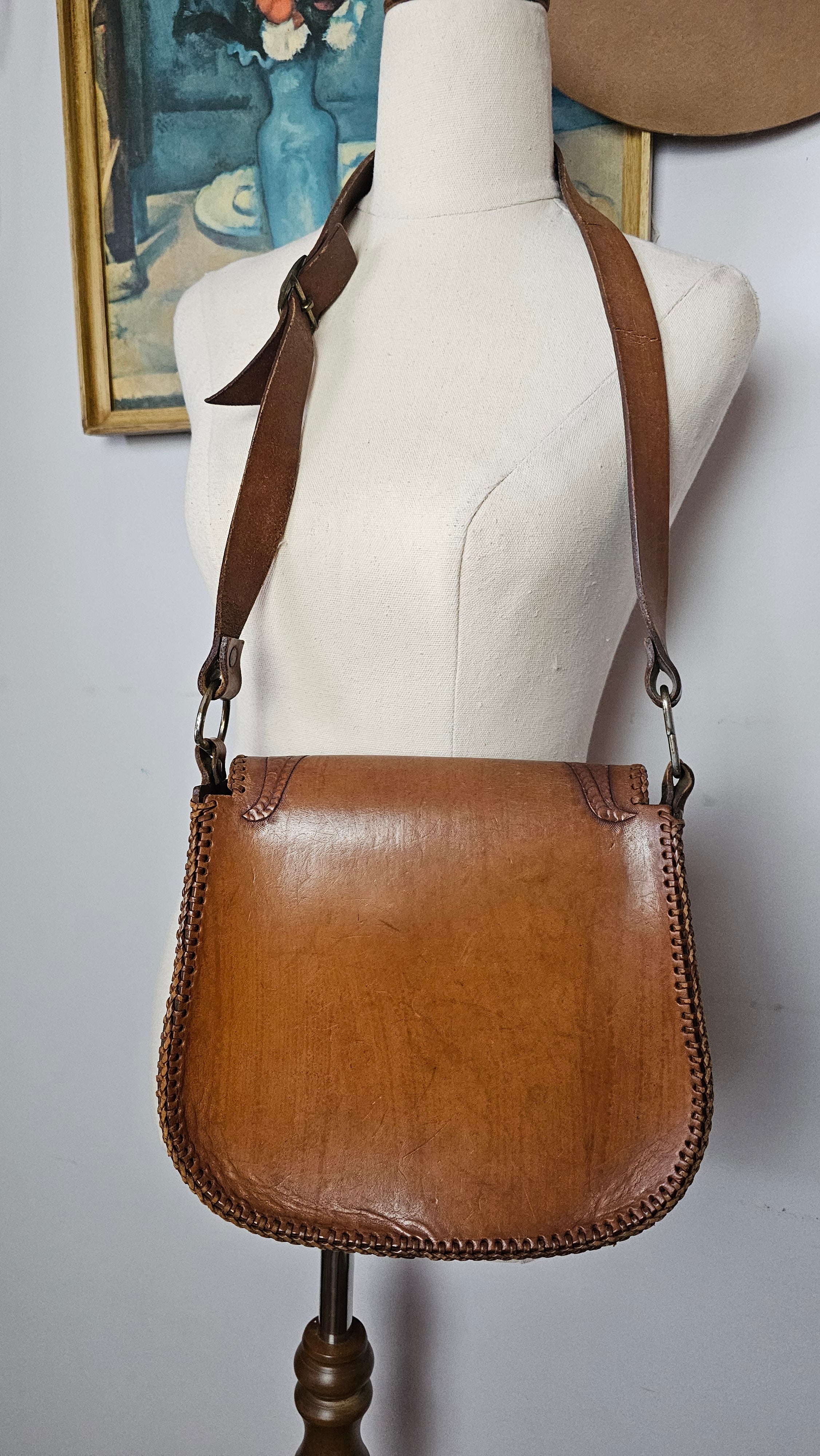 Brown leather handbag on a mannequin against a plain background