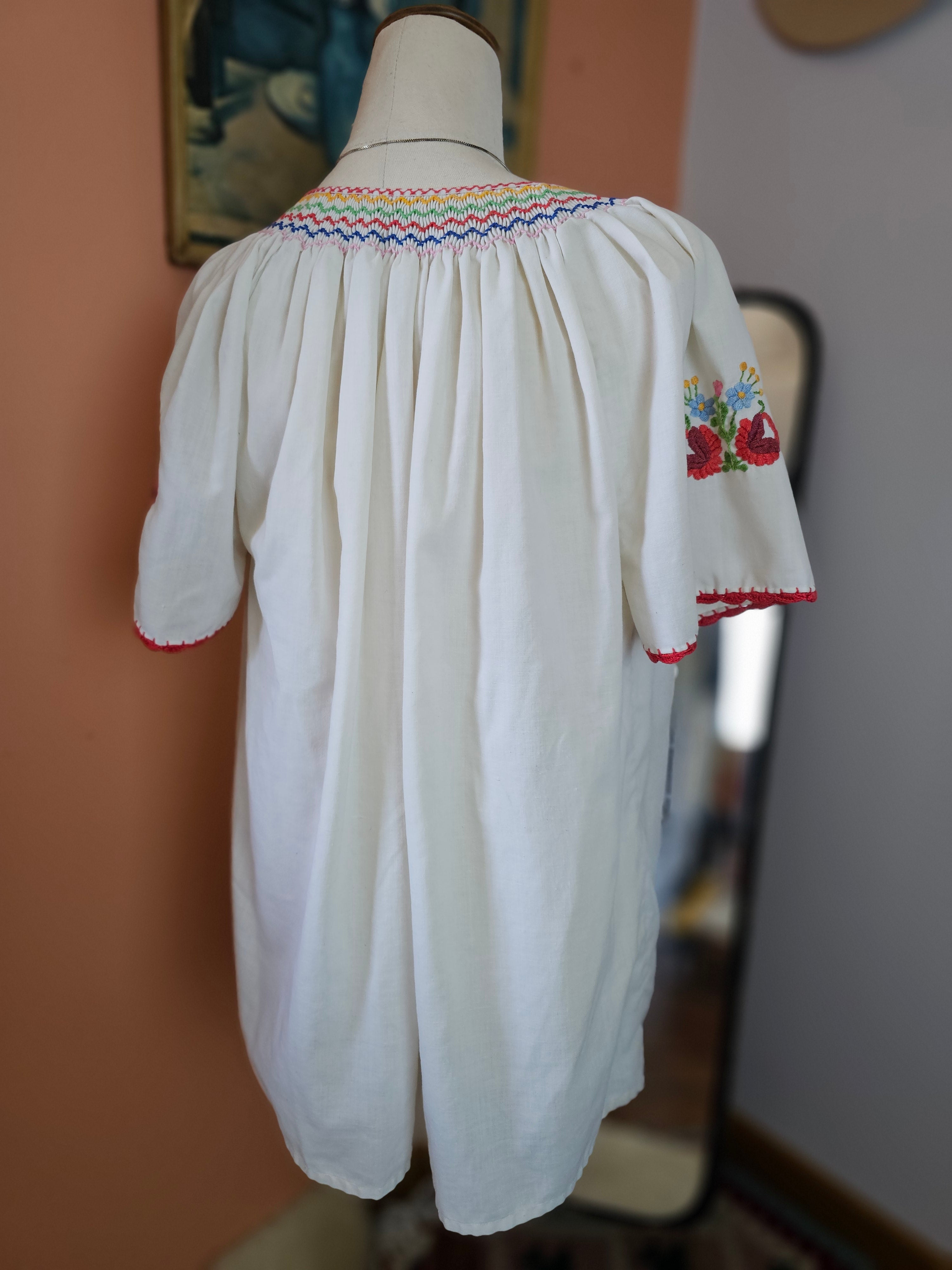 White fabric with colorful embroidery on a wooden stand against a blurred background