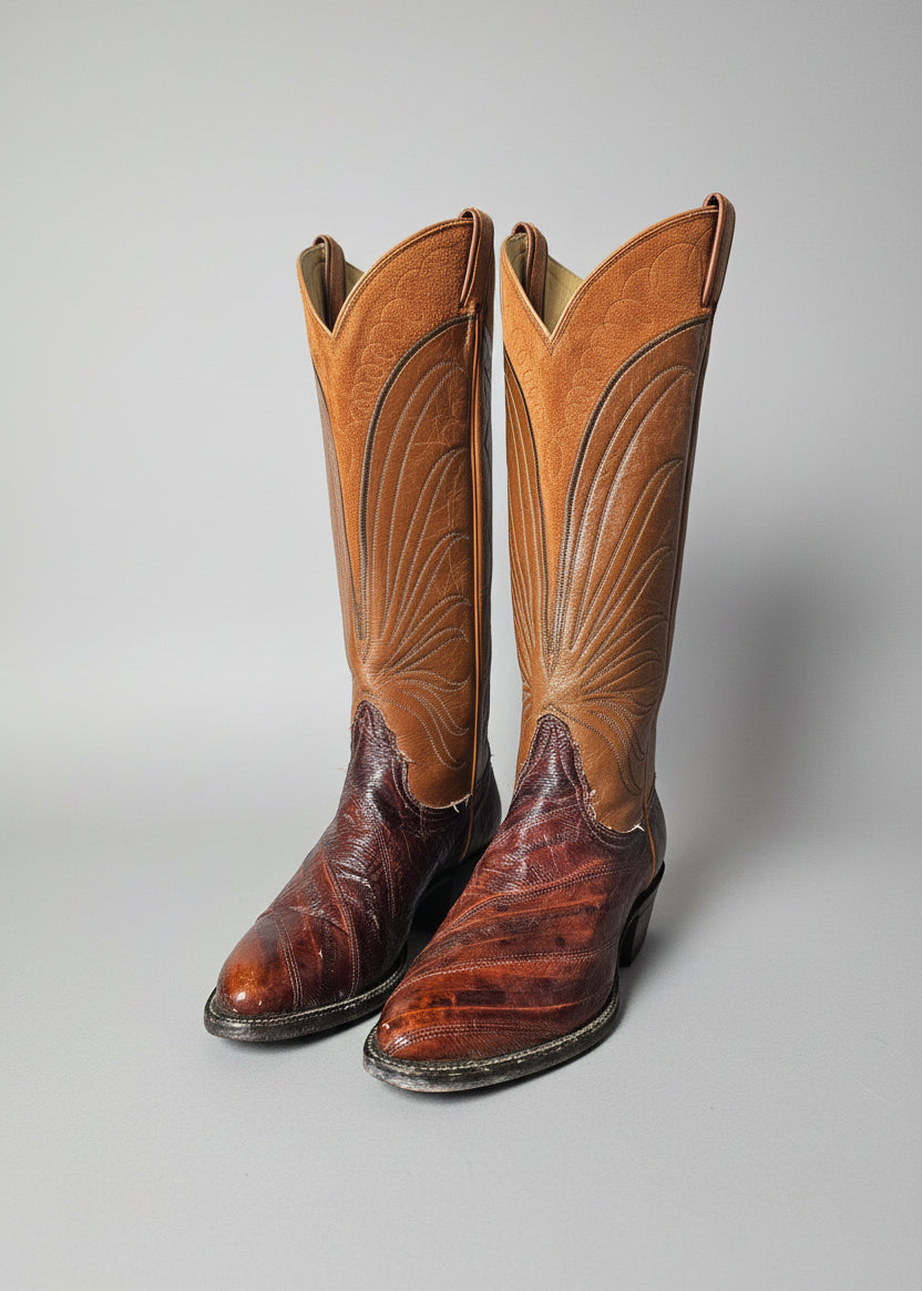 Pair of brown Tony Lama leather boots with intricate designs on a decorative stand.
