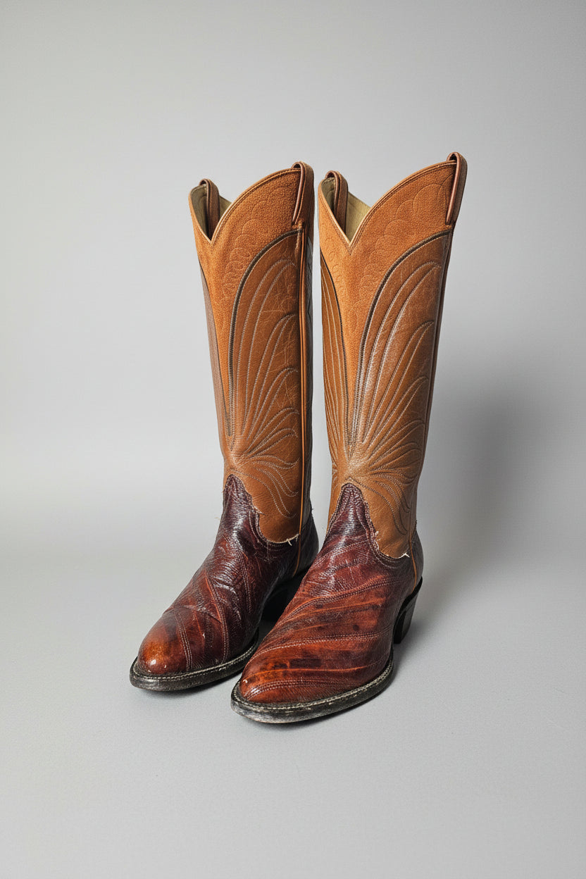 Pair of brown Tony Lama leather boots with intricate designs on a decorative stand.