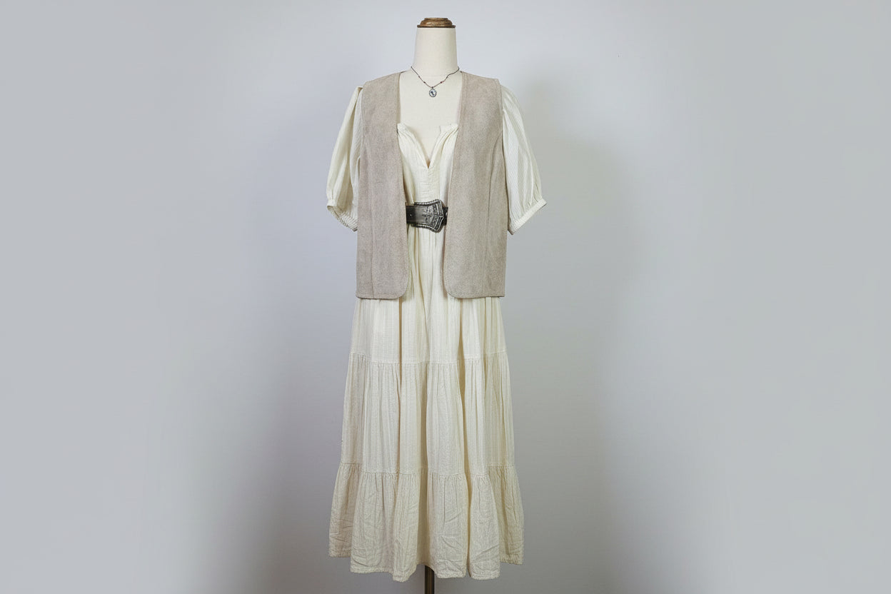 Mannequin wearing a beige trench coat with a hat and floral patterned fabric in the background