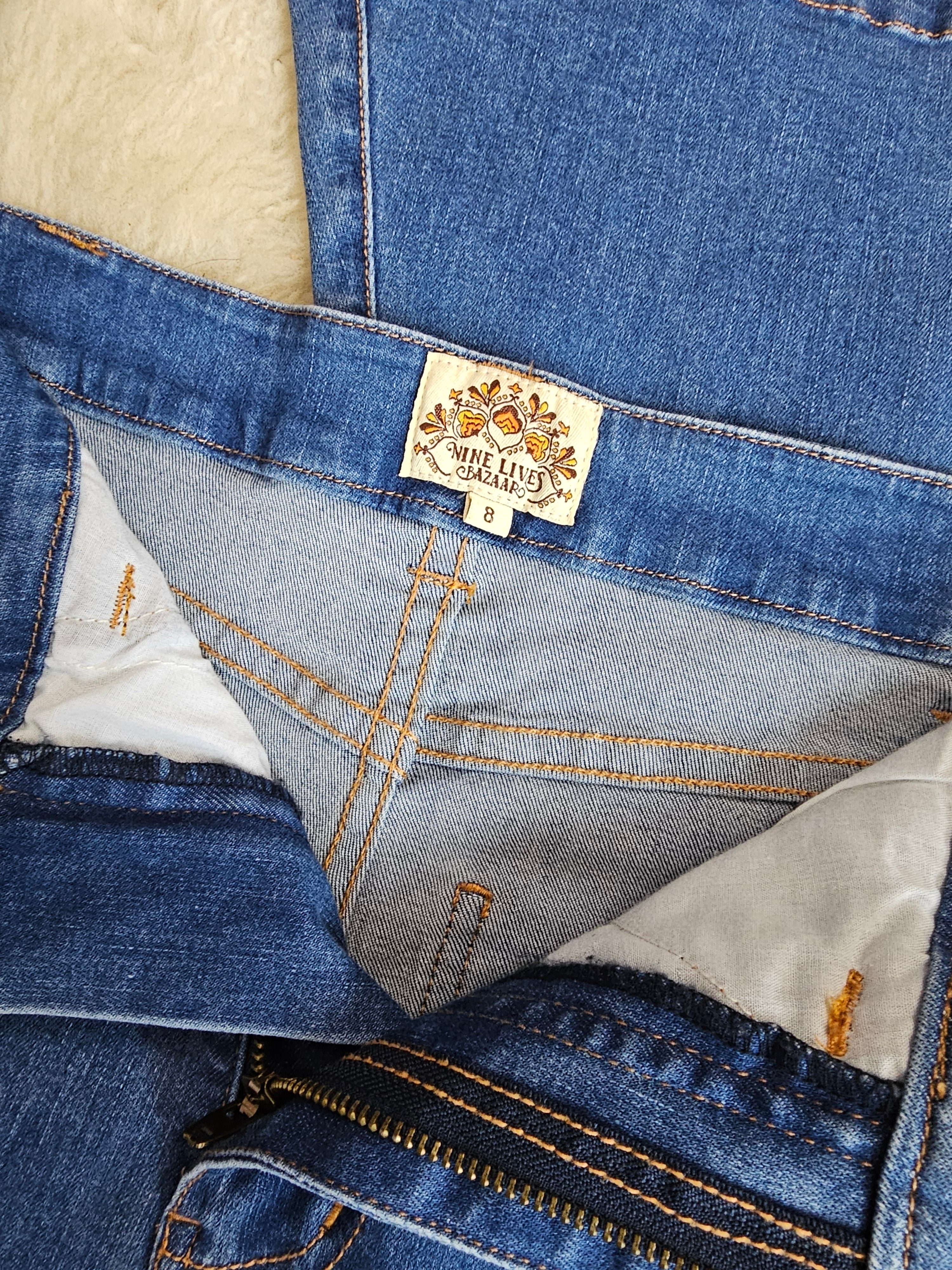 Close-up of a denim jacket with a brand label on a neutral background