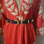 Red fabric with gold embroidery and black buckles on a white background