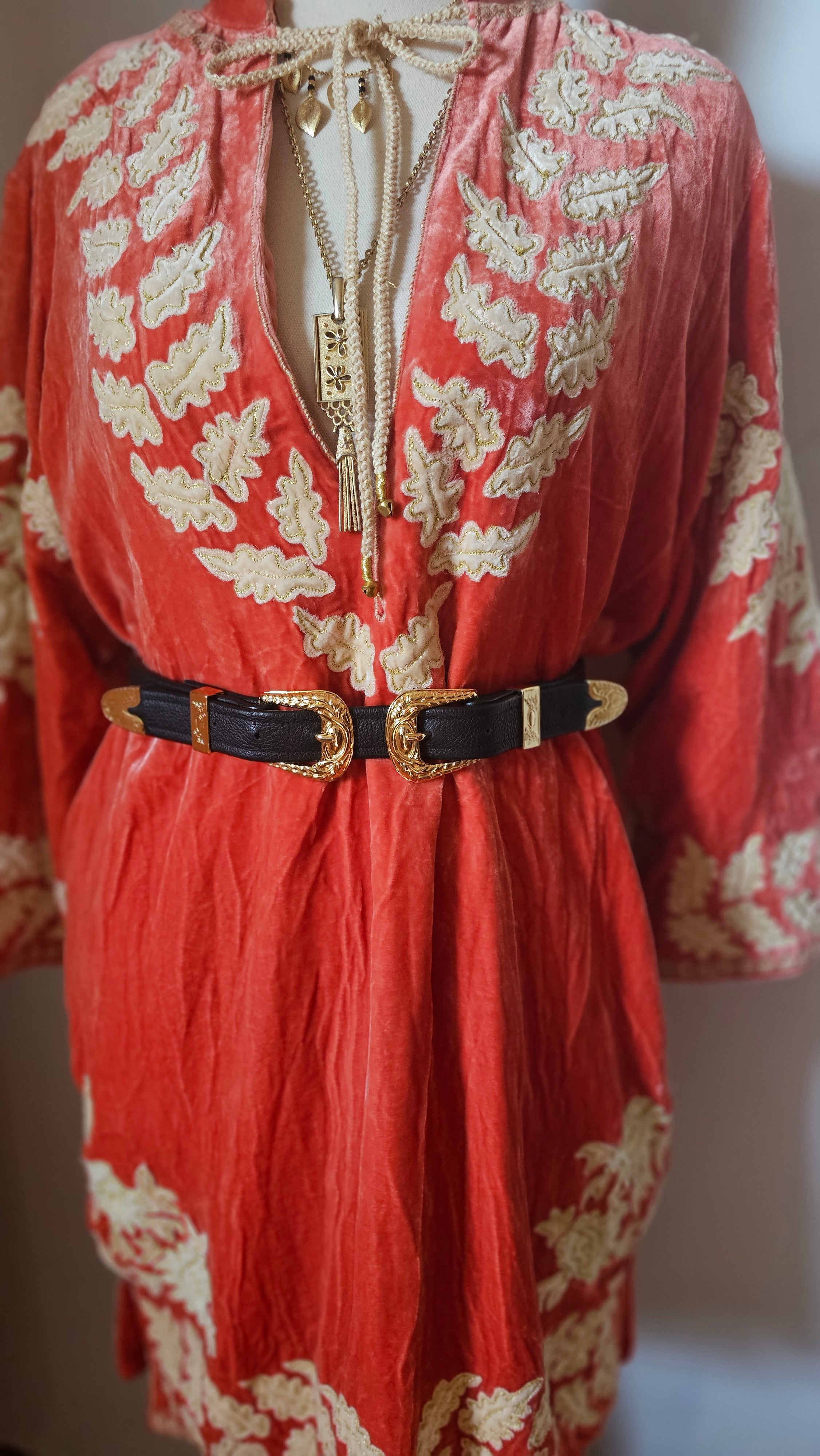 Red fabric with gold embroidery and black buckles on a white background