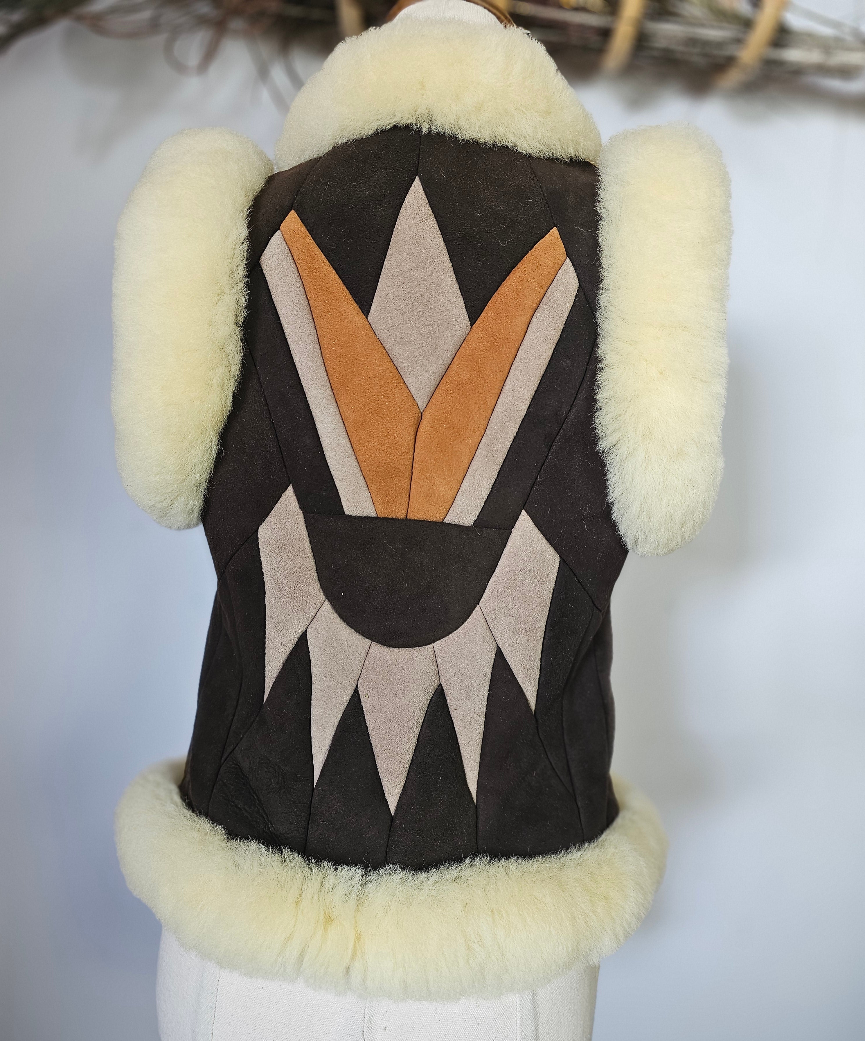 Dog coat with geometric pattern and fur trim on a mannequin against a white background