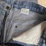 Close-up of a blue denim jacket with a brand label and white lining.
