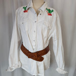 White shirt with floral embroidery on a mannequin against a plain background