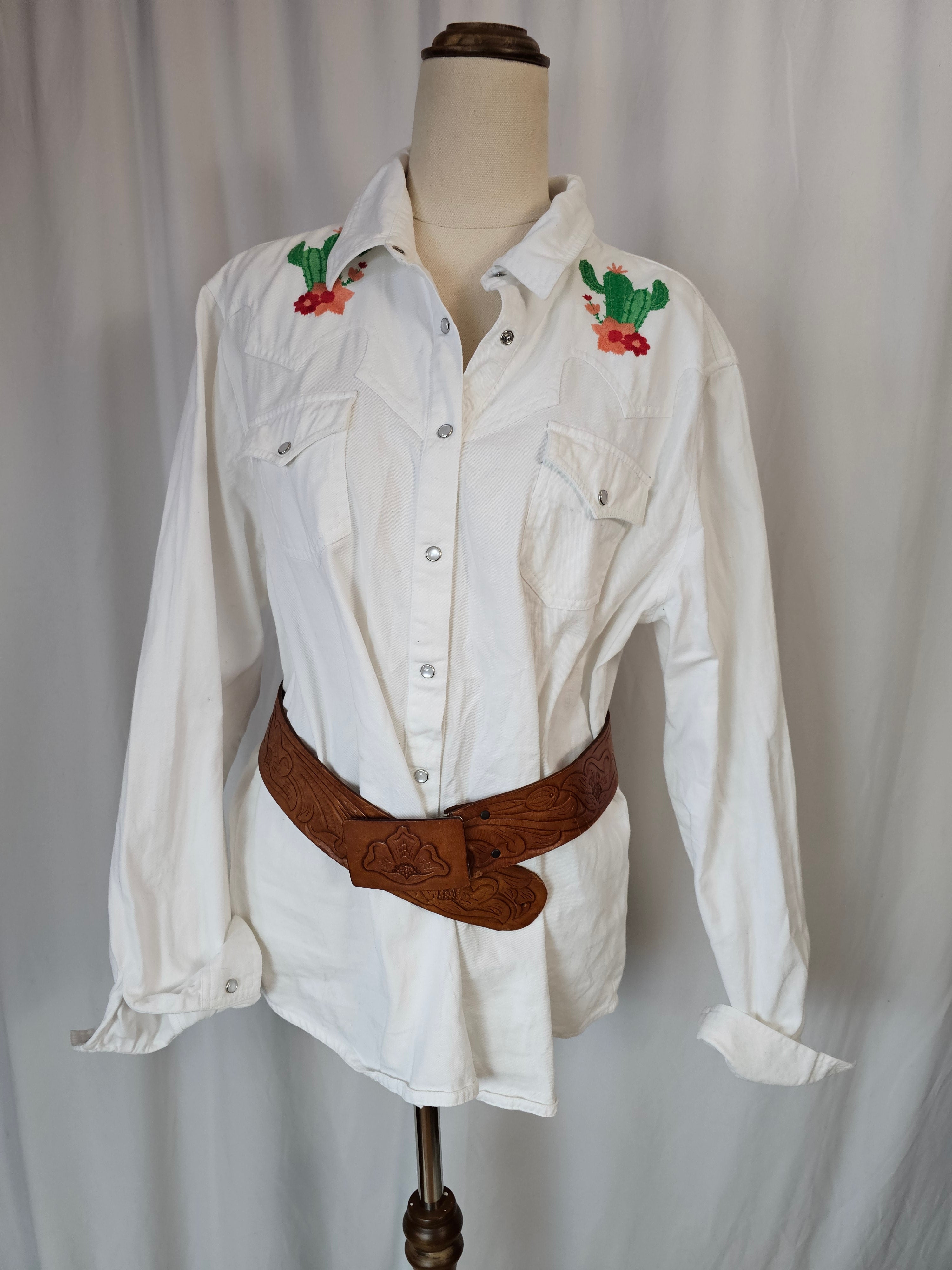 White shirt with floral embroidery on a mannequin against a plain background