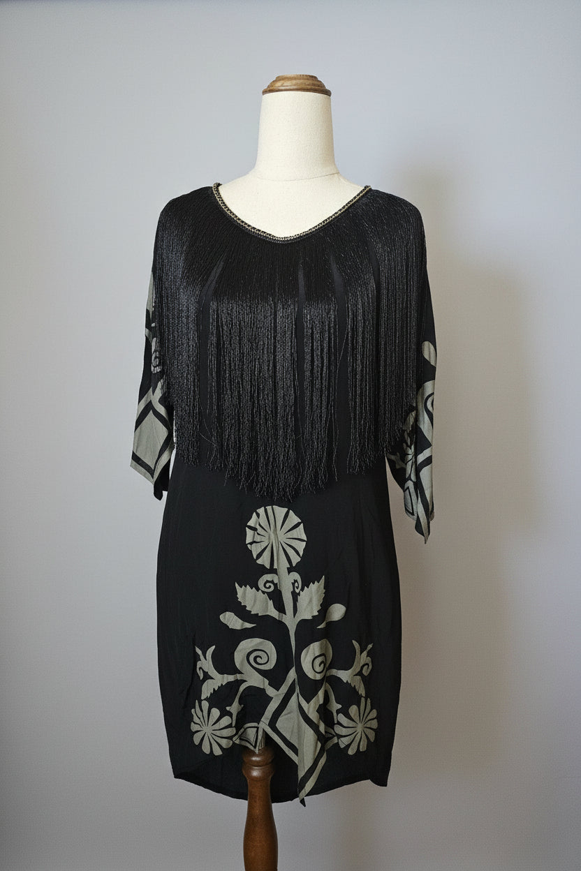 Black dress with white floral embroidery on a mannequin against a plain background