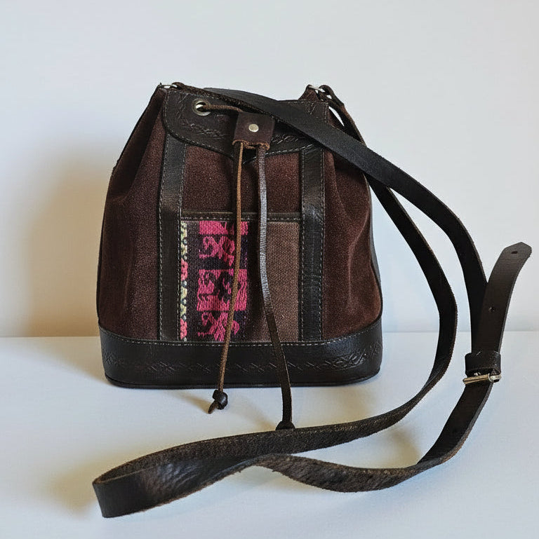 Brown leather bag with a decorative pink pattern on a textured white surface