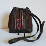 Brown leather bag with a decorative pink pattern on a textured white surface