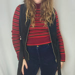 Person wearing a red and black striped sweater with a wide-brimmed hat on a white background