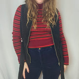 Person wearing a red and black striped sweater with a wide-brimmed hat on a white background